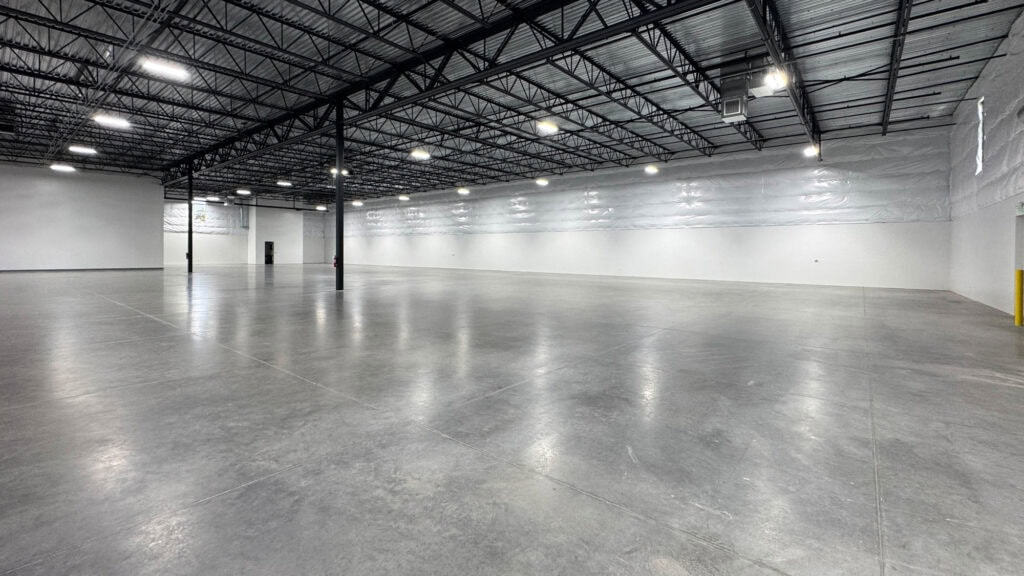 Spacious commercial warehouse with polished concrete floors, metal roof, and ample lighting.