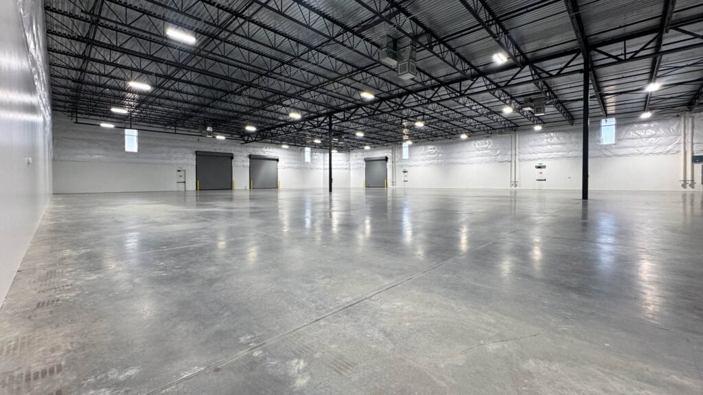 Spacious commercial warehouse with durable concrete flooring and ample lighting for industrial use.